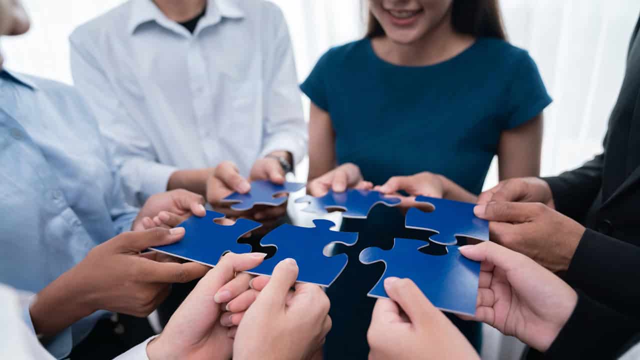 Team holding blue puzzle pieces together.
