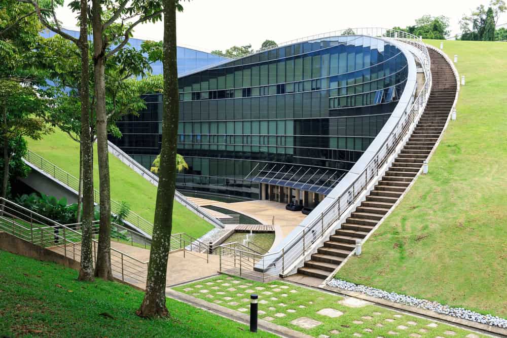 Modern building with curved design on green hill.