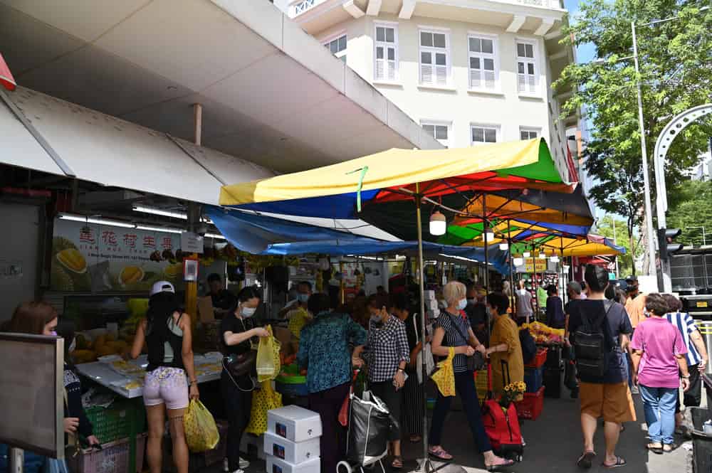 Busy market with colourful umbrellas and shoppers.