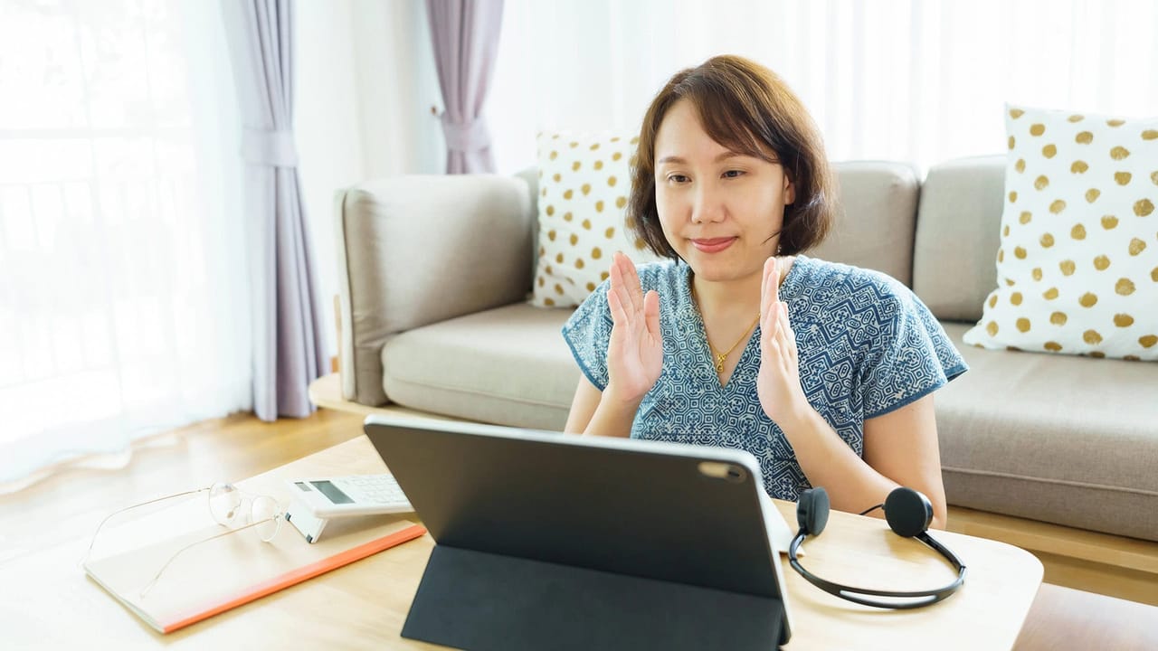 Woman using tablet for video call at home