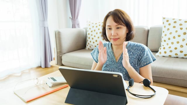 Woman using tablet for video call at home