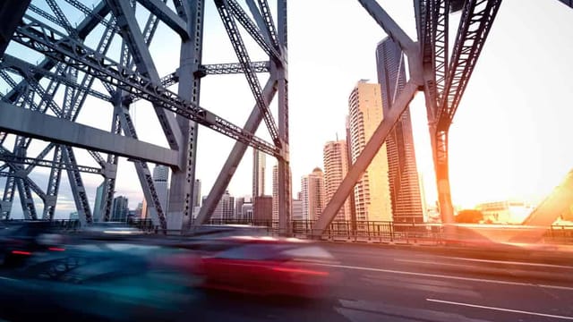 Traffic crossing bridge with city skyline at sunset.