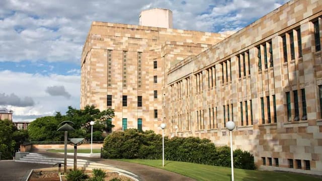 University sandstone building with garden and walkway.