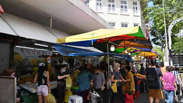 Busy market with colourful umbrellas and shoppers.