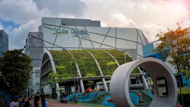 JCube shopping centre exterior with greenery and sculpture.