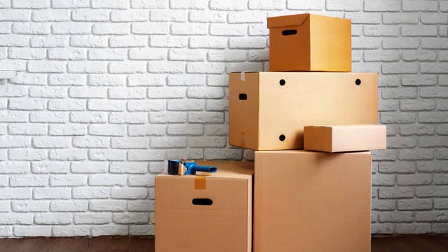 Stacked cardboard boxes against white brick wall.