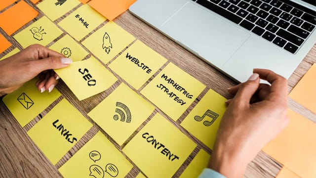 Person organising website strategy sticky notes on desk that include SEO and Content.