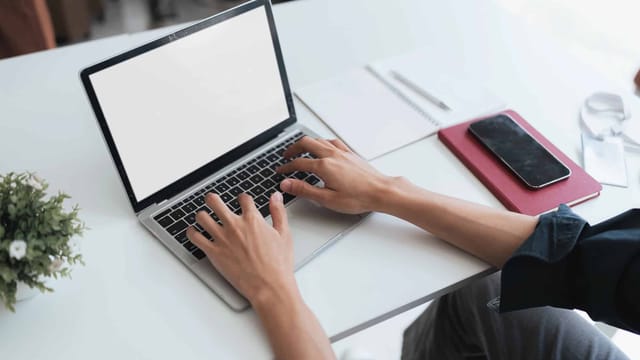 Person typing on laptop at white desk