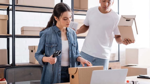 Two people scanning and packing small boxes for online customer delivery