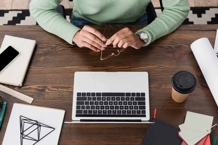 Person working at desk with laptop and coffee