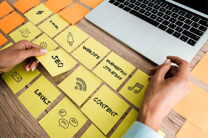 Person organising website strategy sticky notes on desk that include SEO and Content.