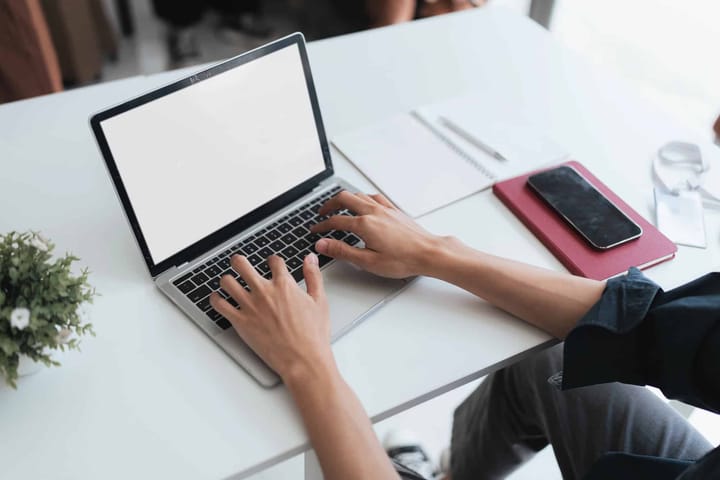 Person typing on laptop at white desk
