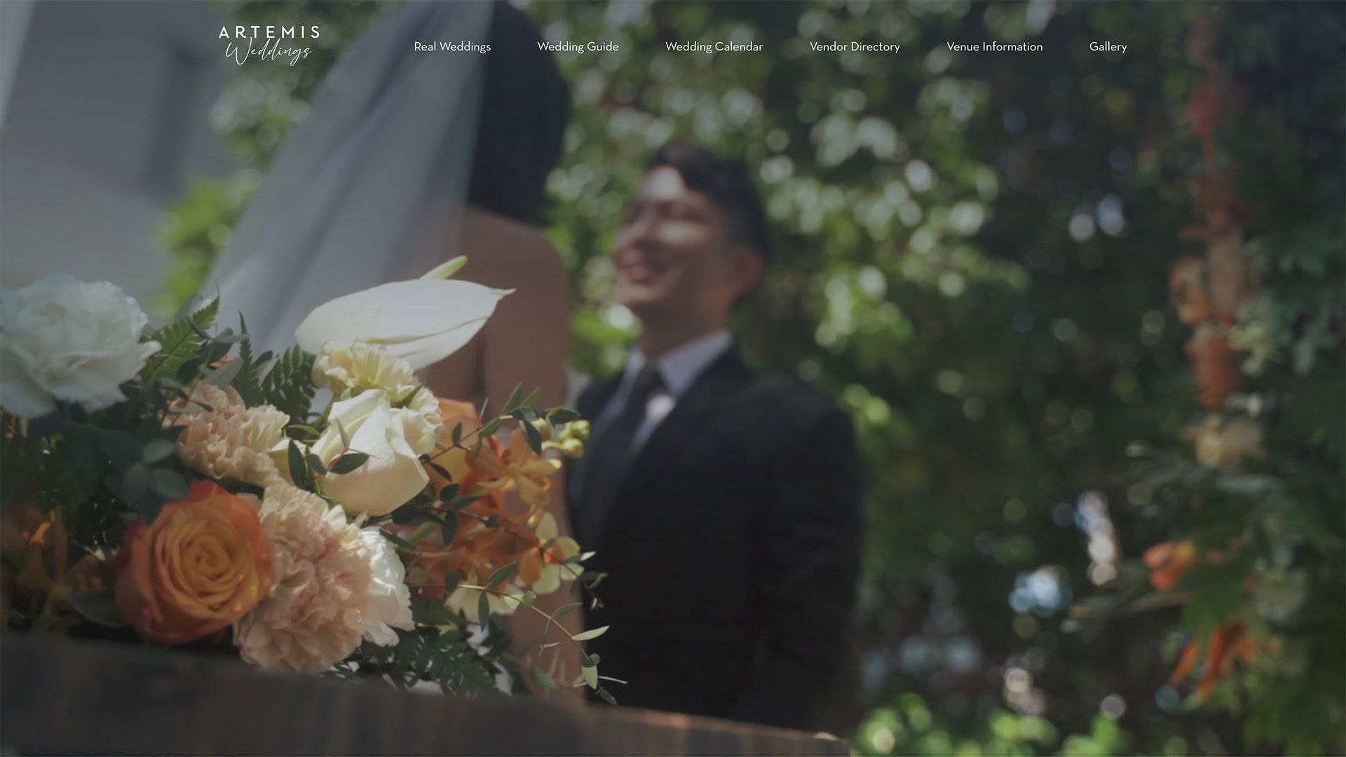 Groom smiling behind floral arrangement at wedding