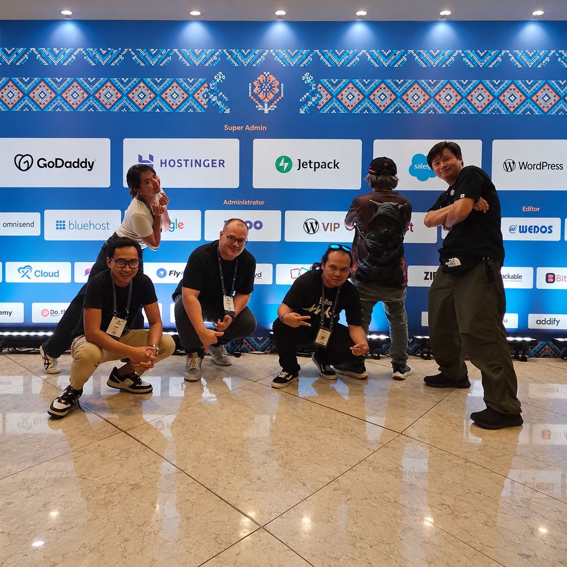 Attendees posing before WordPress conference sponsor backdrop