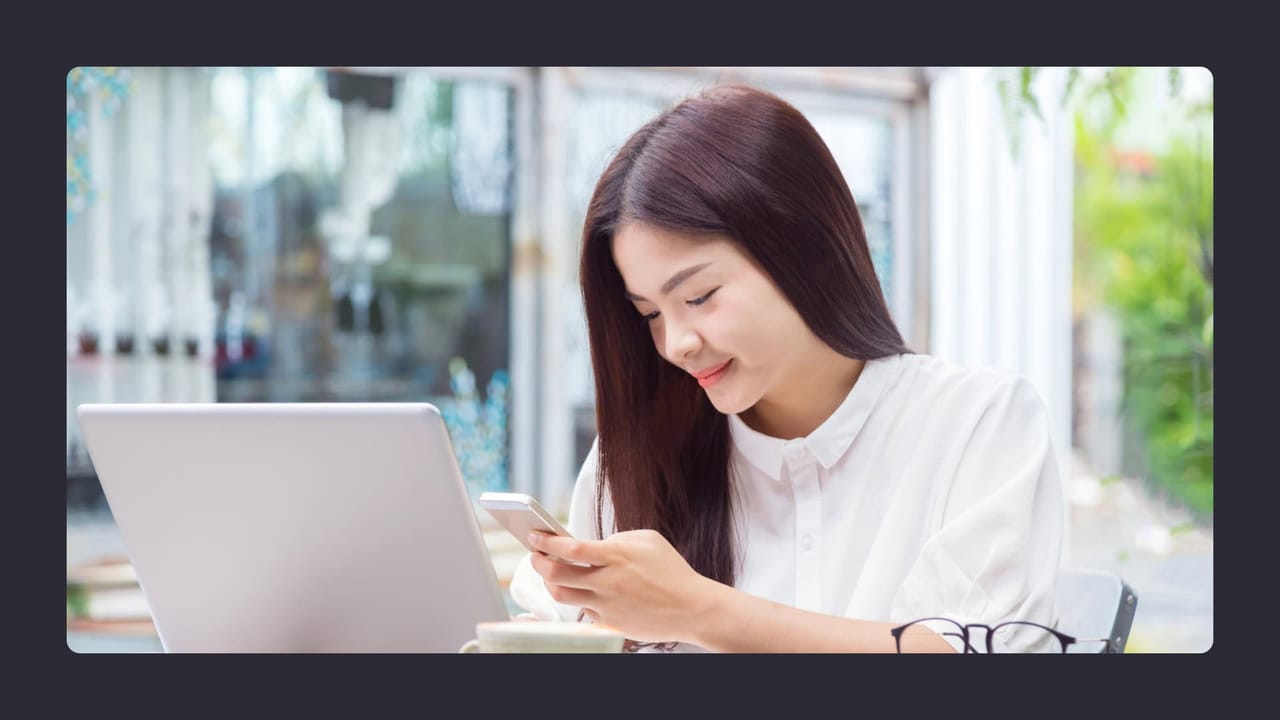 Woman using smartphone and laptop at cafe