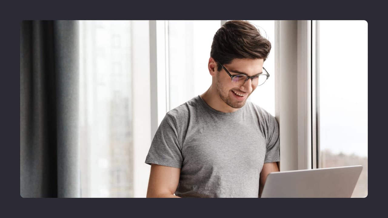 Smiling man using laptop near window