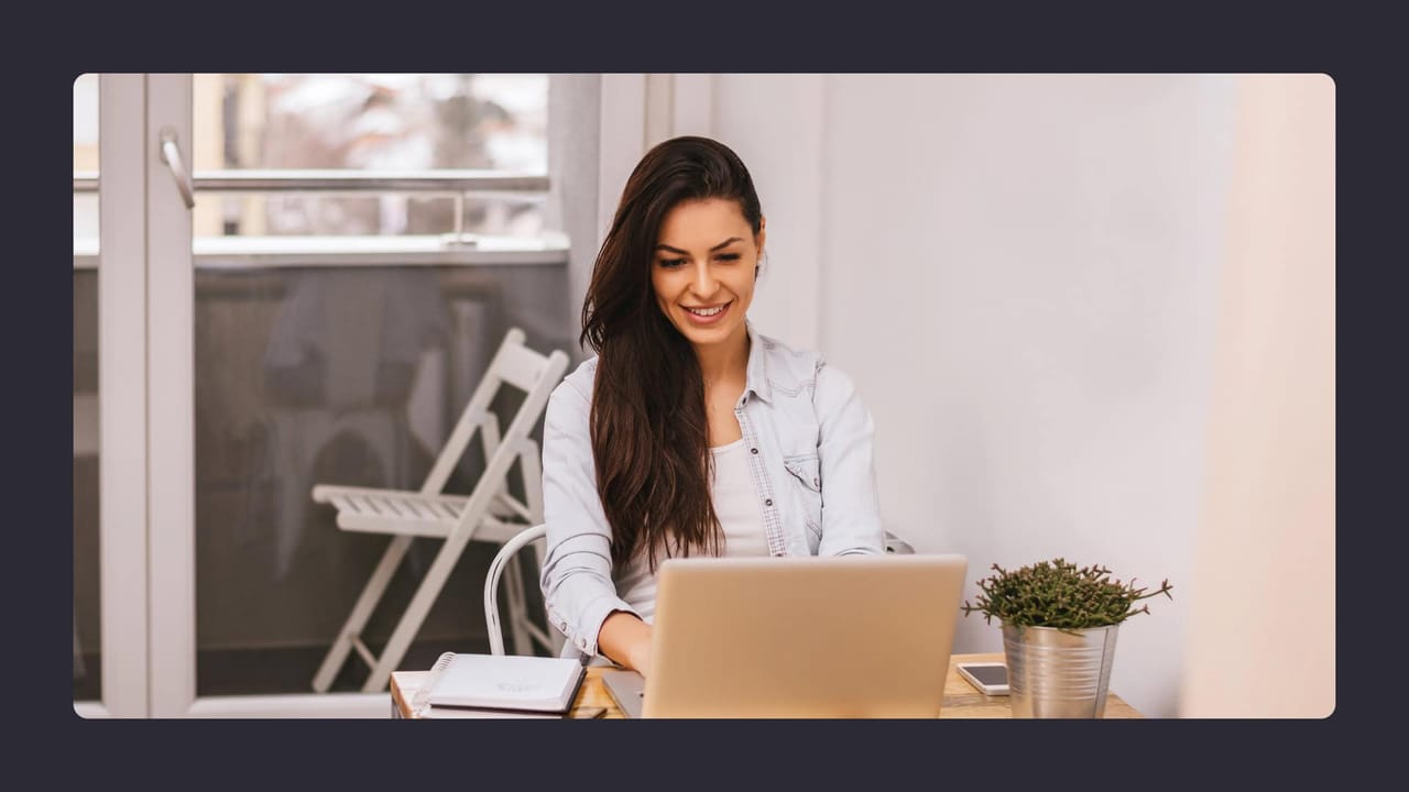 Woman smiling, working on laptop in bright room