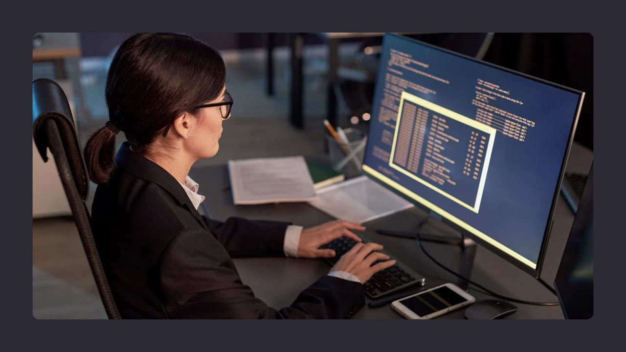 Programmer analyzing code on computer screens at night