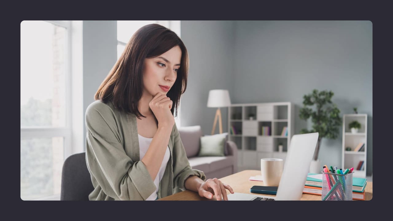 Woman pondering at desk with laptop and coffee