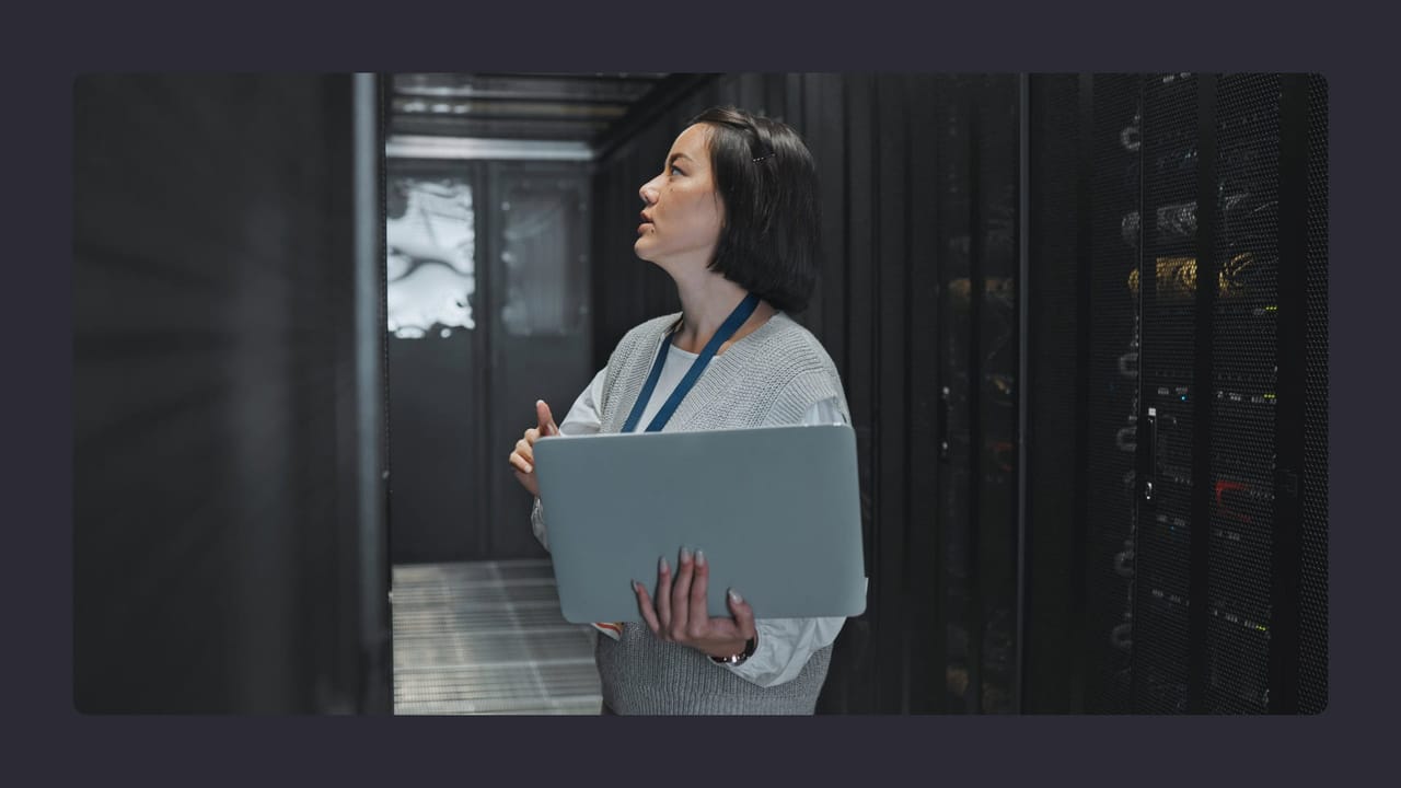 Woman inspecting servers with laptop in data center