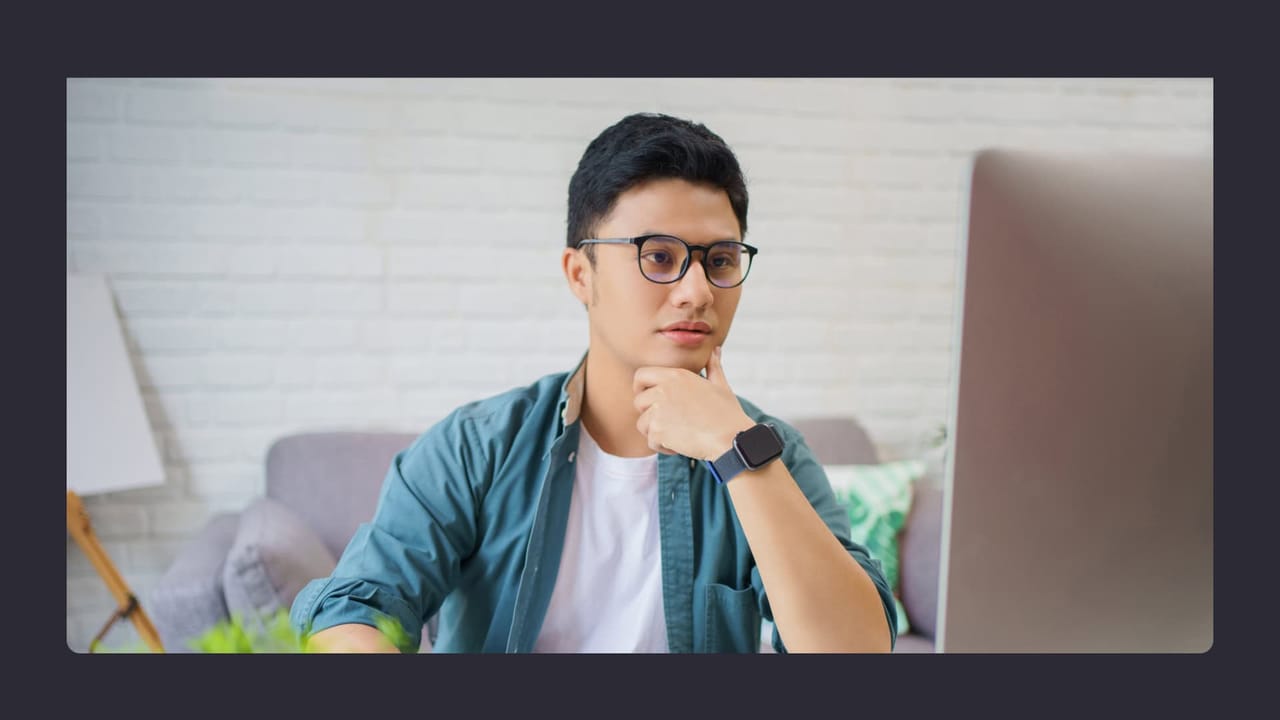 Young man with glasses using laptop in modern room