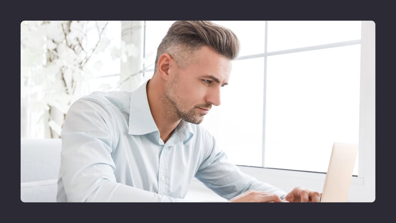 Focused man working on laptop in bright office