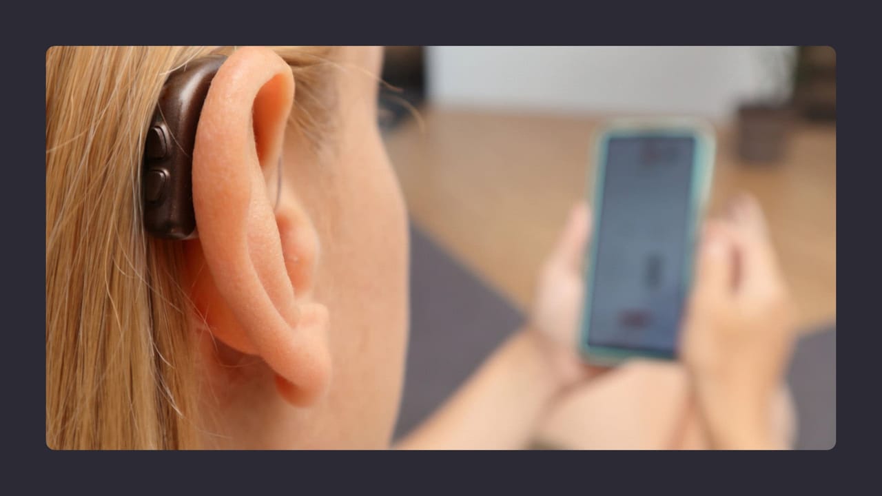 Woman using smartphone with hearing aid visible