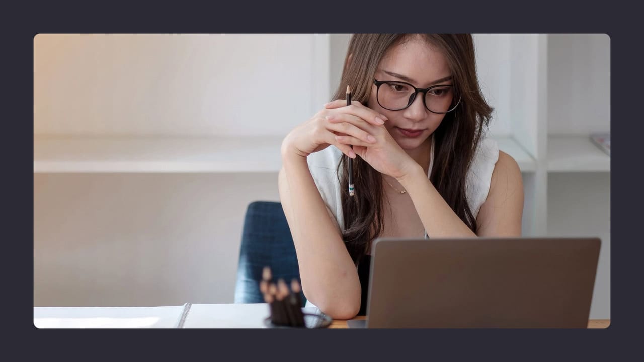 Woman wearing glasses using laptop intensely