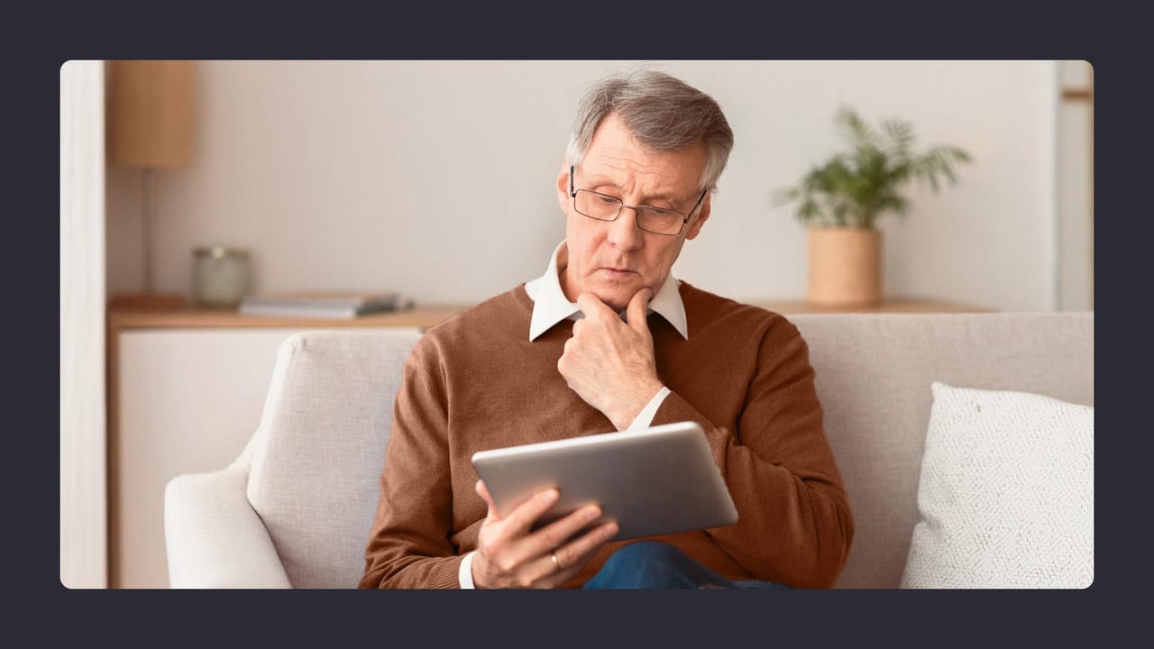 Senior man using tablet on couch at home