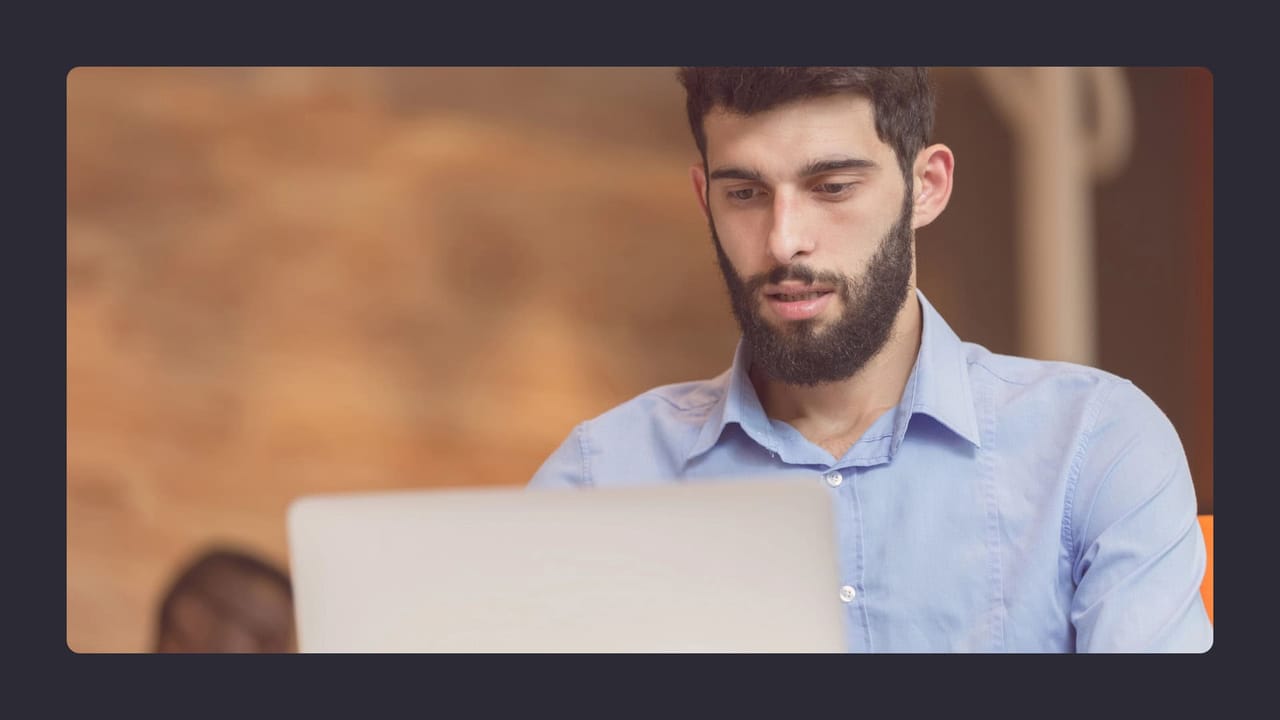 Bearded man using laptop in casual office setting