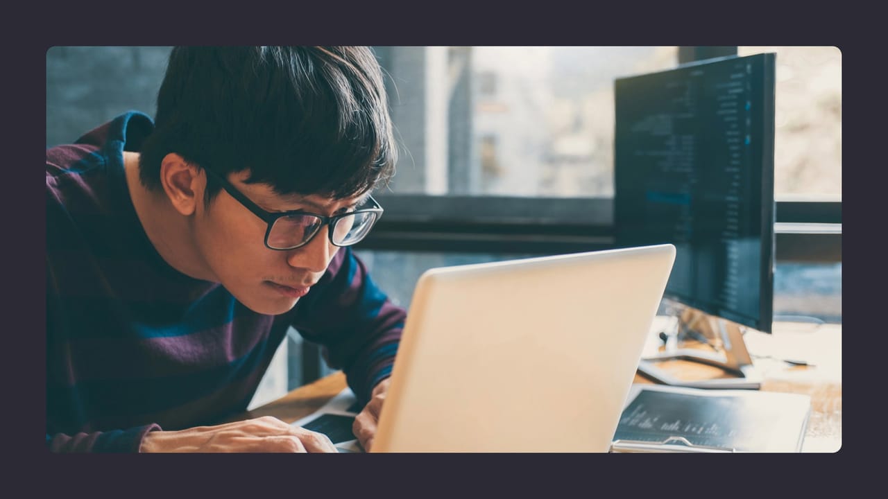 Man examining laptop closely in tech-filled workspace