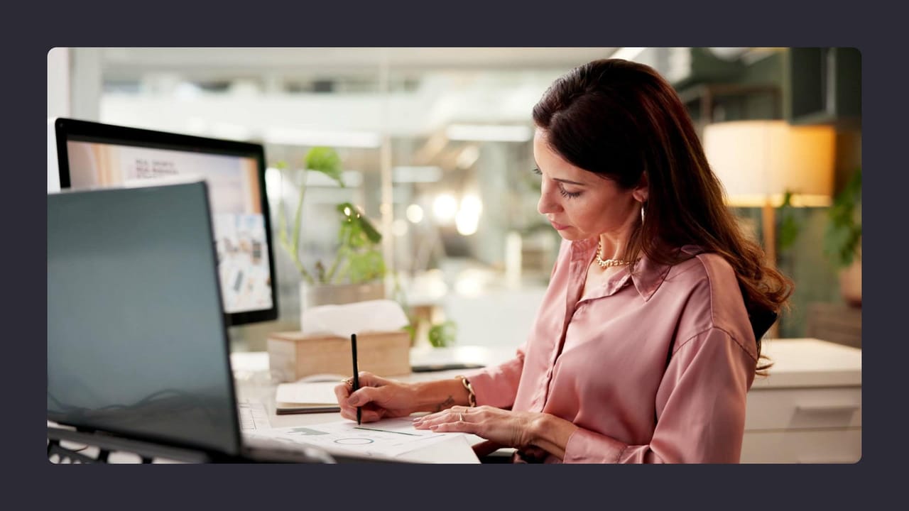 Woman sketching in office, using computer and desk