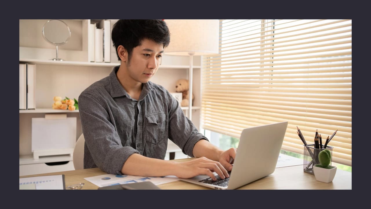 Man typing on laptop at home office desk