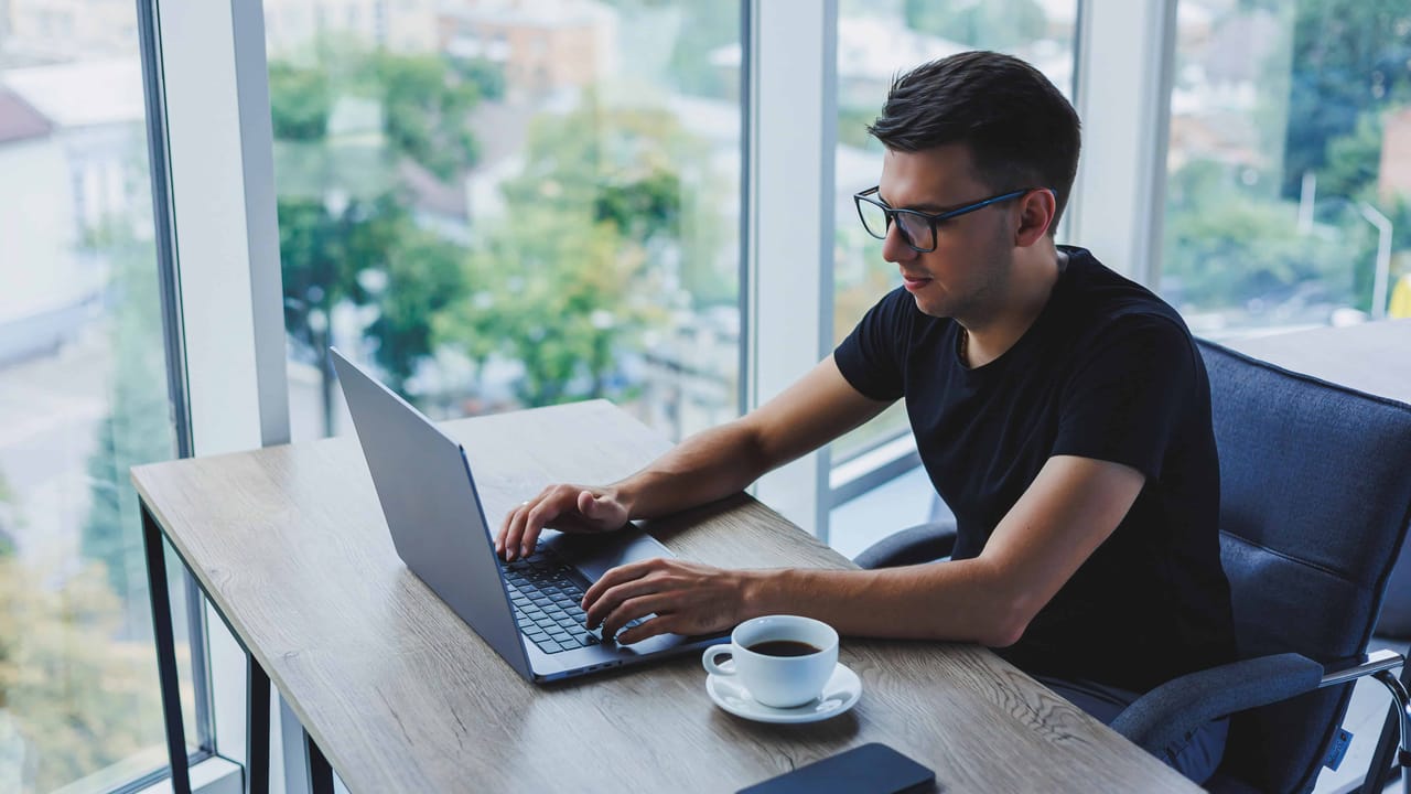 Man working on laptop near window