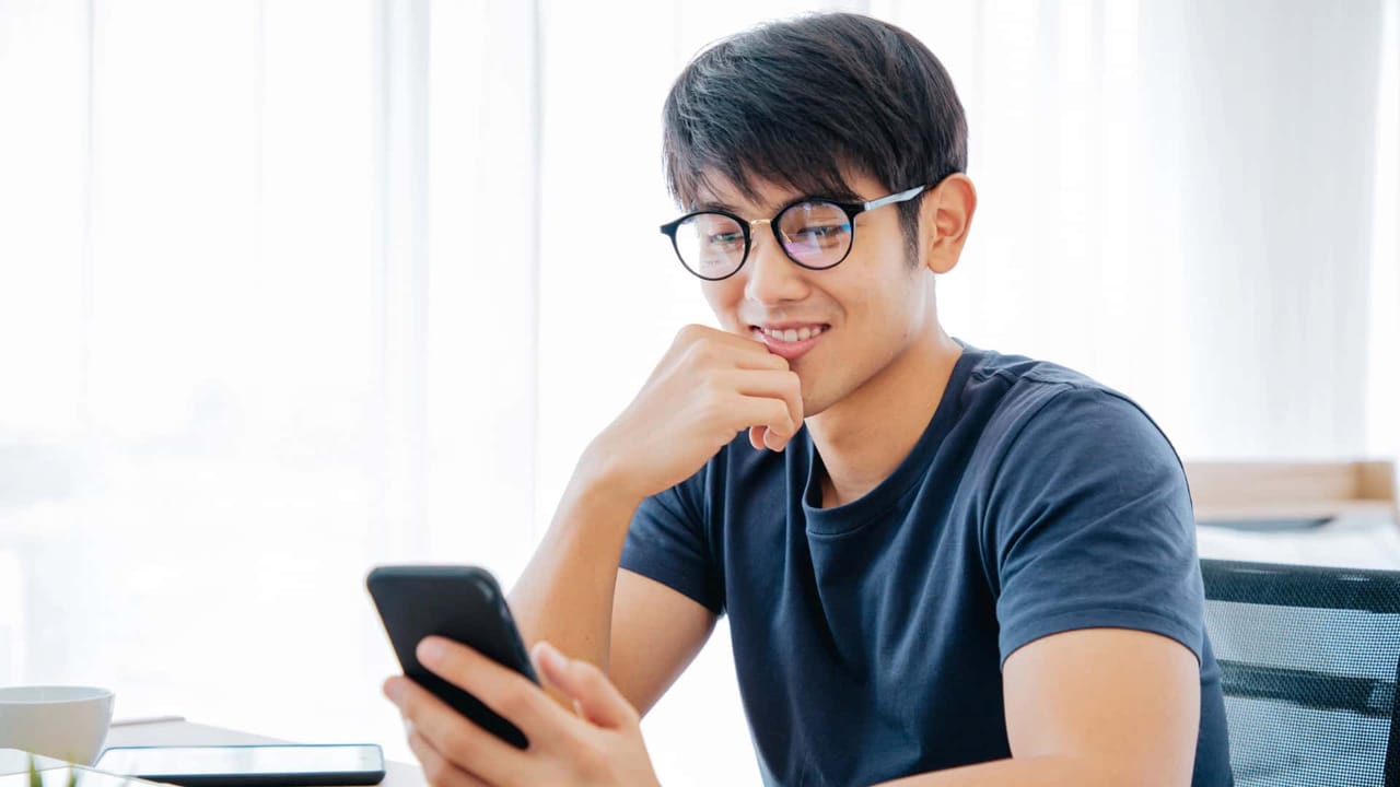 Person smiling at smartphone indoors.