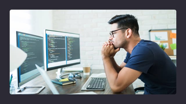 Man analysing code on computer screens in office