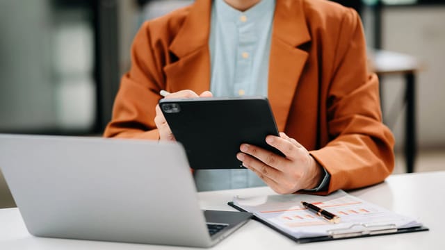 Businessman using tablet and laptop at modern office desk