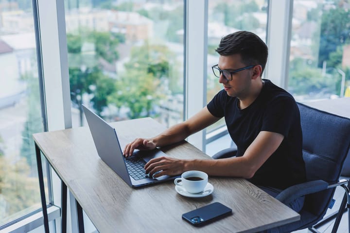 Man working on laptop near window