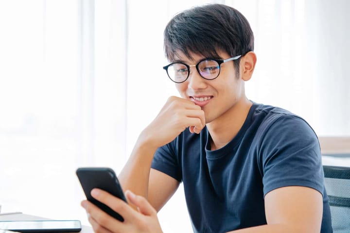 Person smiling at smartphone indoors.
