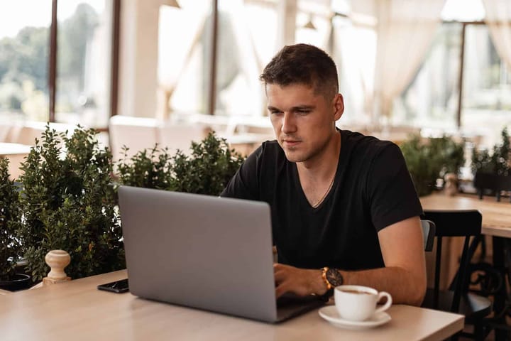 Man working on laptop in café setting.