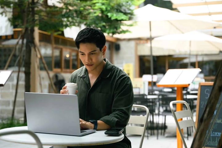 Man working on laptop in outdoor cafe