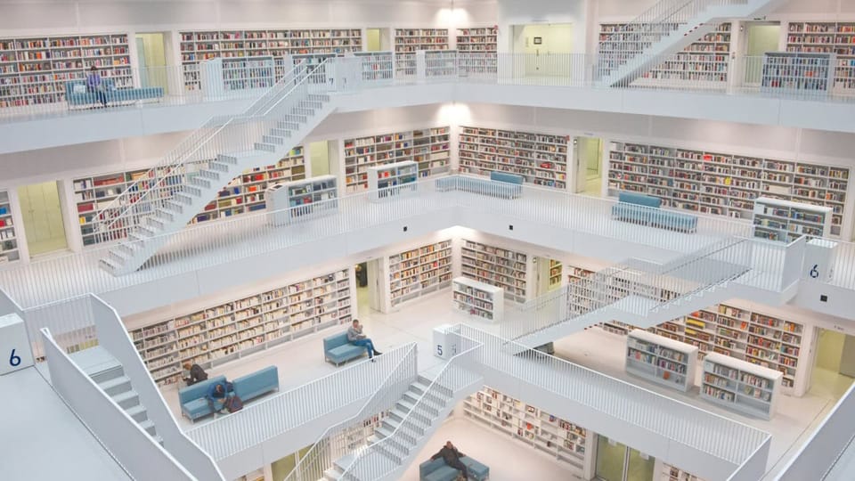 Modern multi-level library interior with staircases and bookshelves.