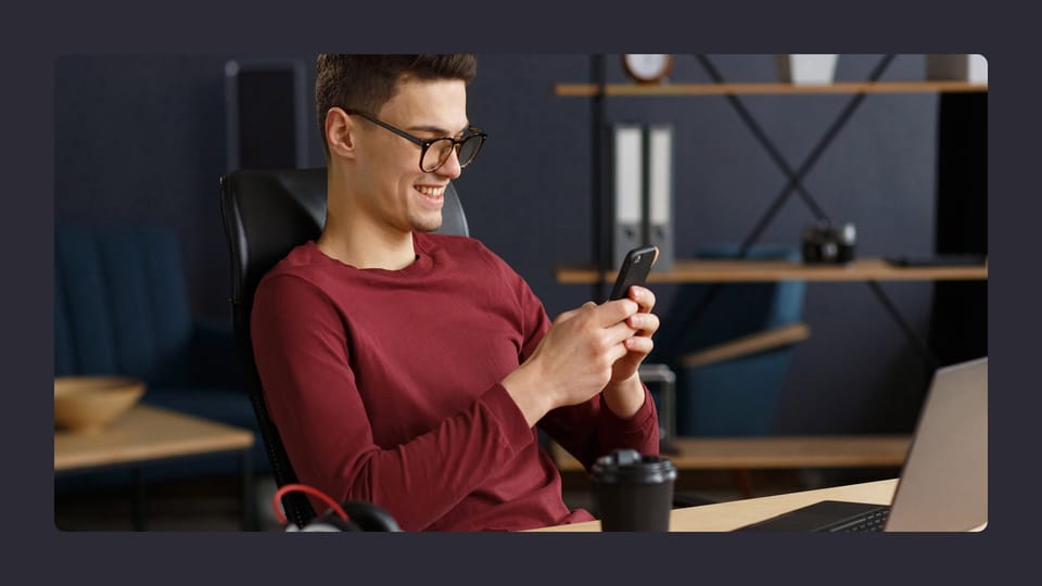 Man smiling at phone in modern office setting