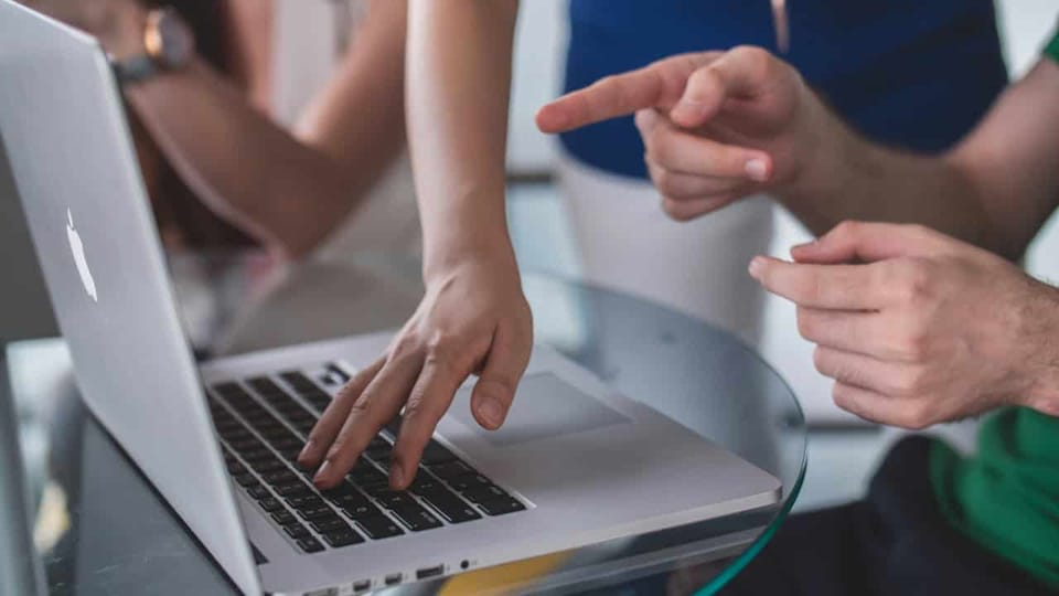 People collaborating on laptop work task.