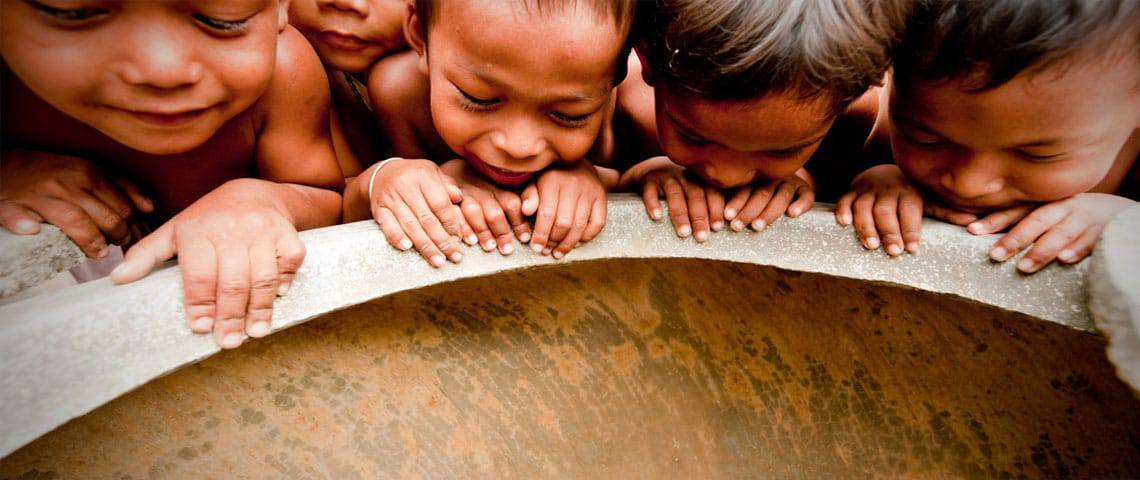 Five Asian kids peering down a water well 1140 x 480 pixels