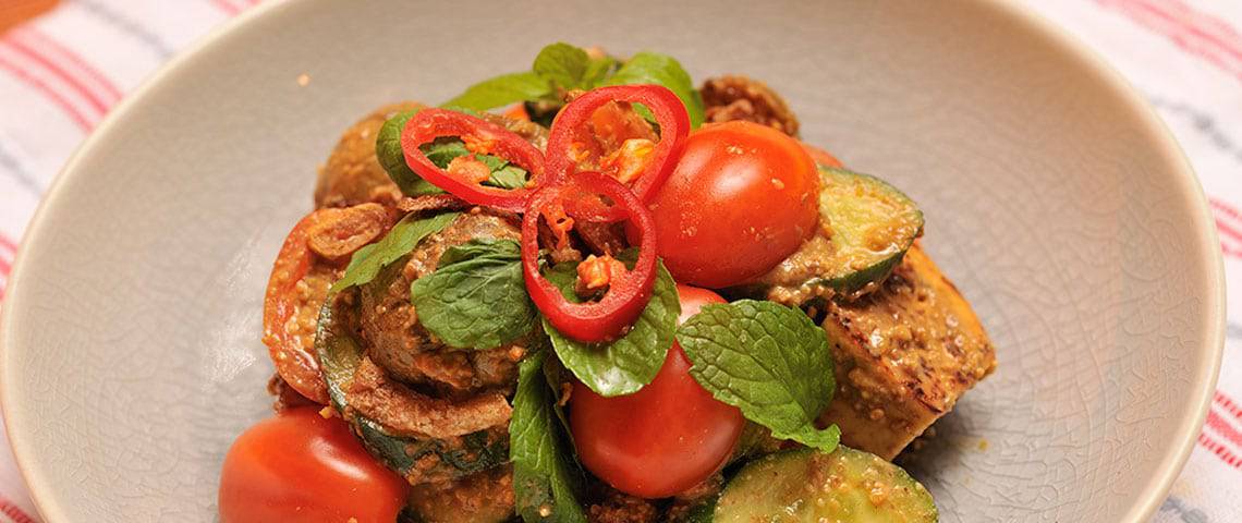 Zucchini dish topped with tomatoes and mint leaves nicely served in a bowl