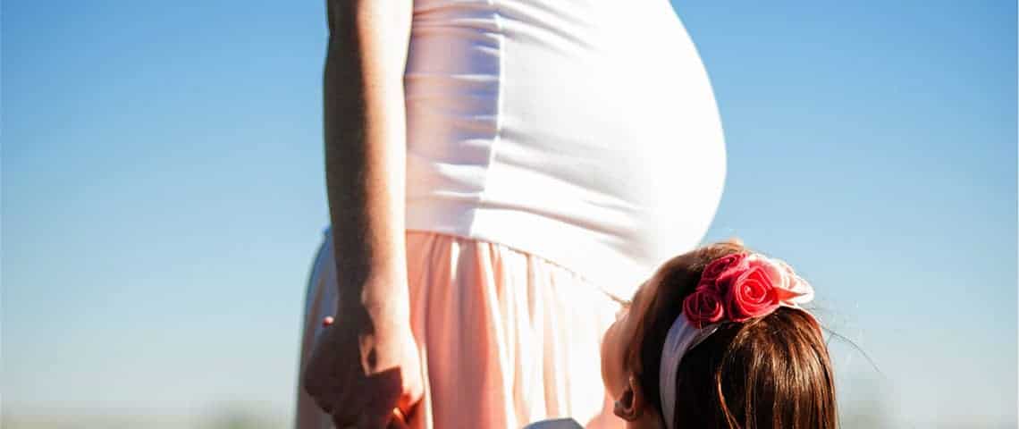 Pregnant belly touched a by young girl