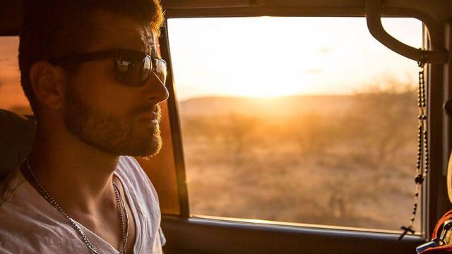 White male wearing dark sunglasses inside a car