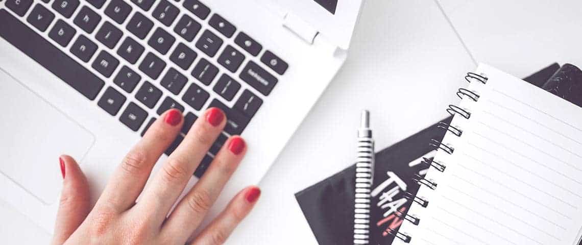 woman using laptop with notebook and pen