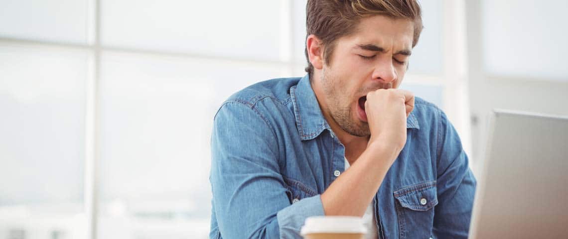 man on a laptop yawning